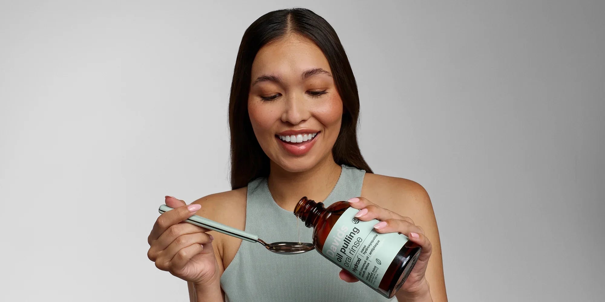 Woman pouring Davids Oil Pulling Oral Rinse into a spoon for proper dosing
