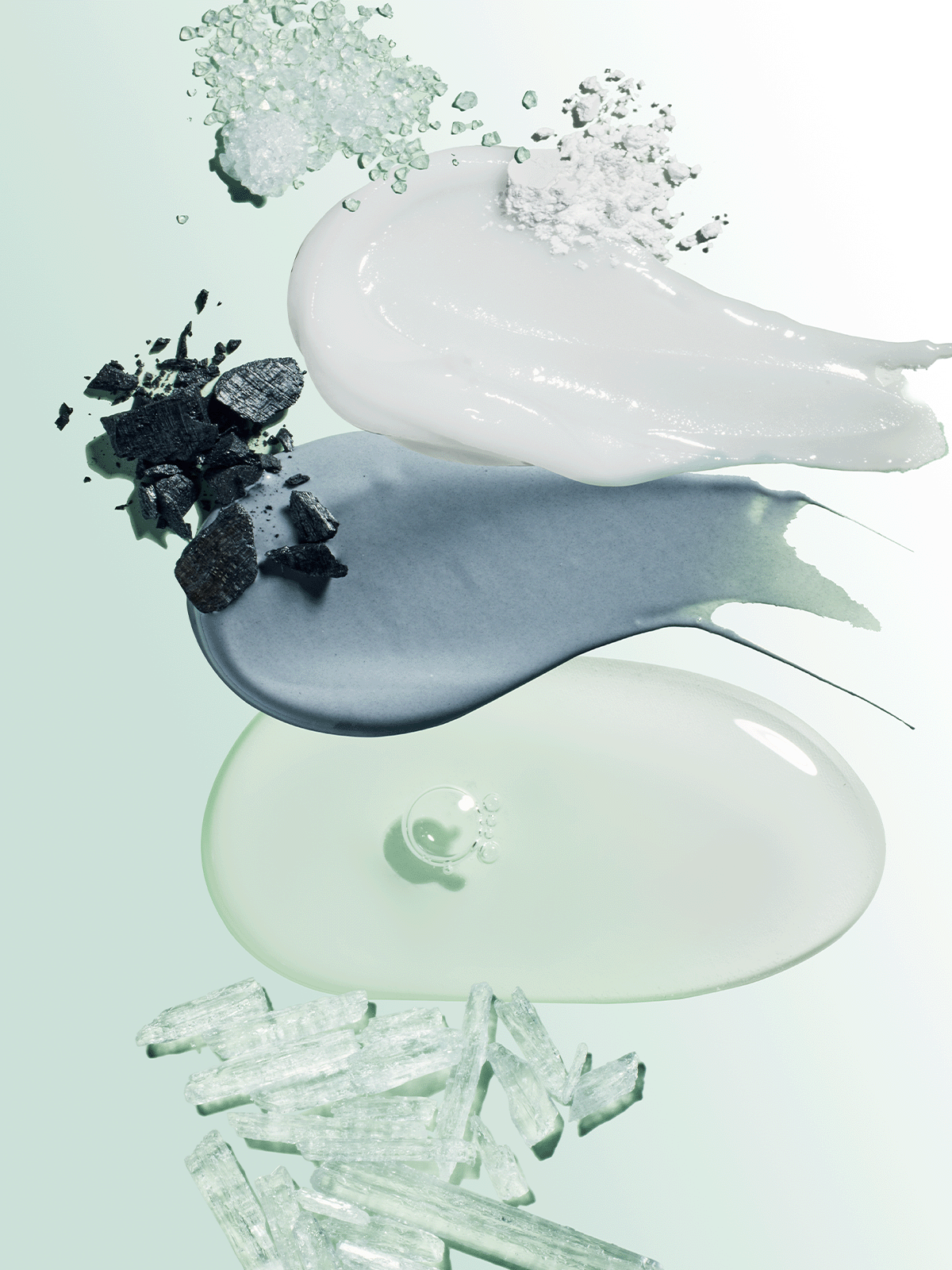 Toothpaste smears with charcoal, salt crystals, and minerals on green background