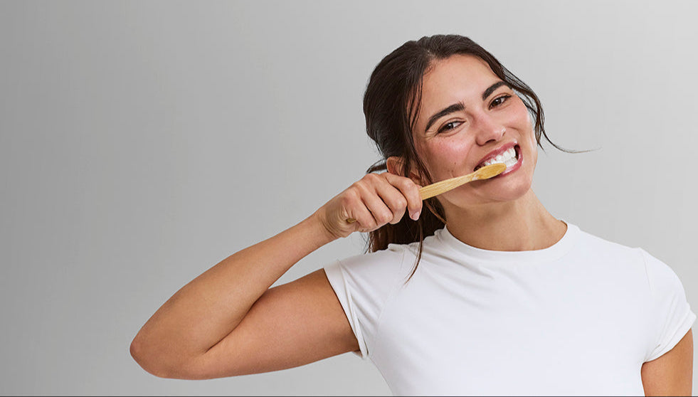 Woman with sensitive teeth brushing with Davids Hydroxi Sensitive and Whitening toothpaste while smiling