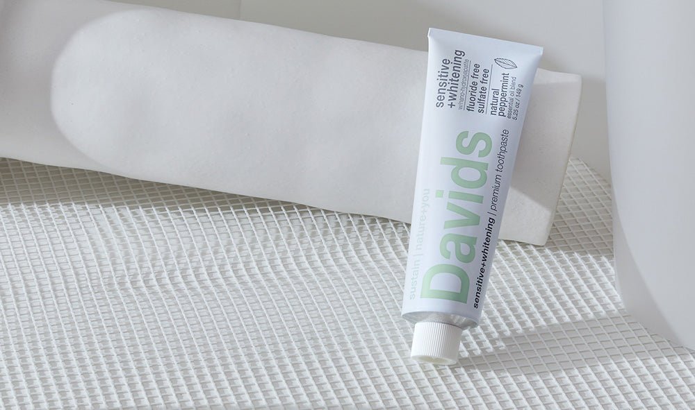 Davids Sensitive + Whitening natural peppermint toothpaste tube displayed on a white textured surface.