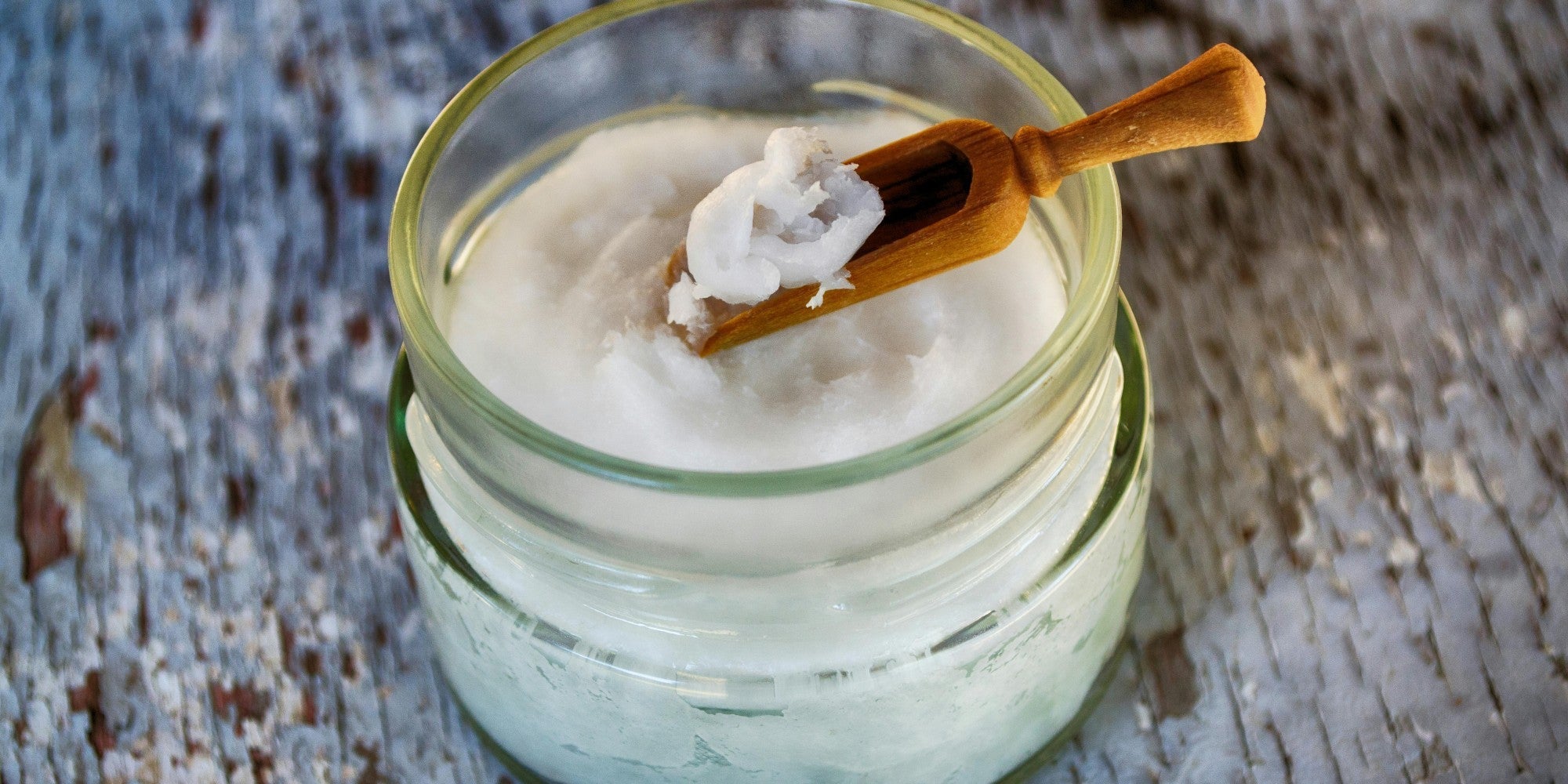 Glass container and wooden spoon with coconut oil