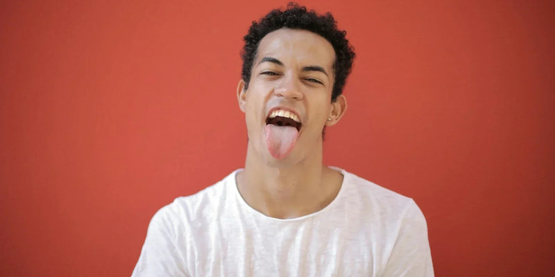 A young man extending his tongue to demonstrate a healthy tongue dorsum microbiome.