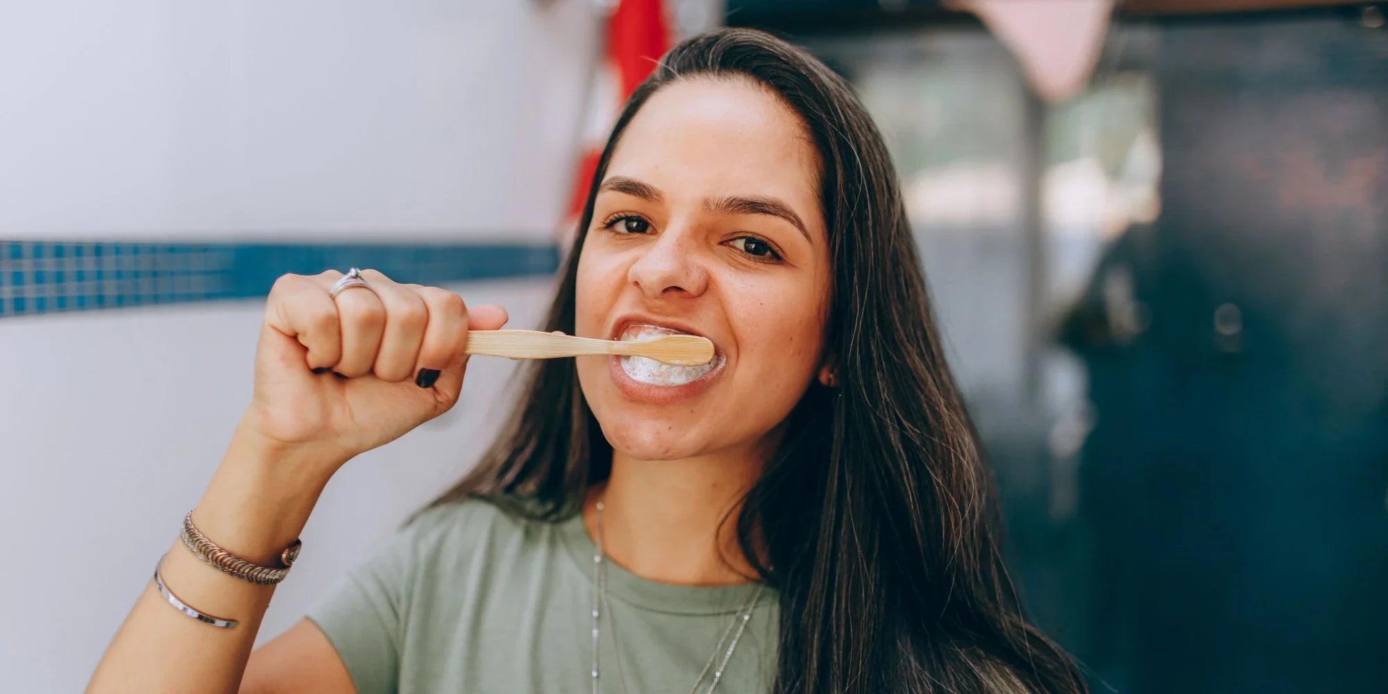 Young woman brushing her teeth with a bamboo toothbrush and foaming toothpaste.