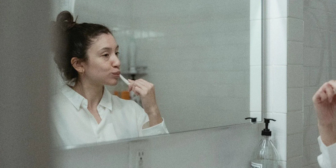 a woman brushing her teeth in front of a mirror