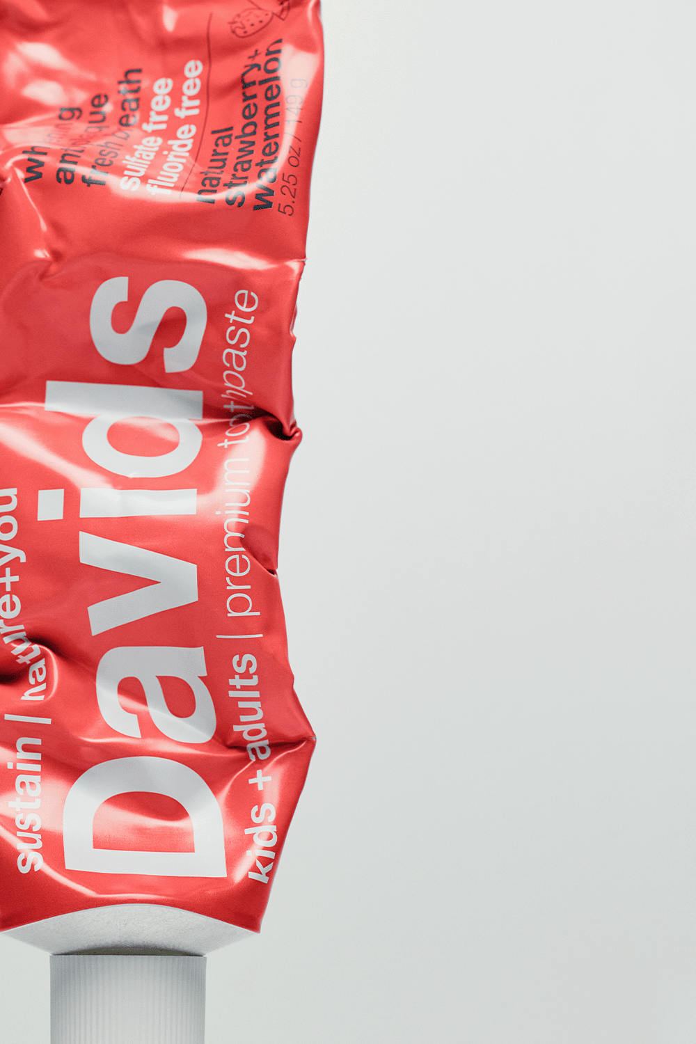 Crinkled red toothpaste tube labeled Davids, kids + adults, premium toothpaste